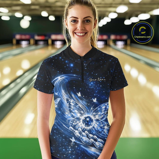 Female model at a bowling lane wearing a blue quarter-zip bowling shirt featuring luminous butterfly wings surrounding a bowling ball on the front.