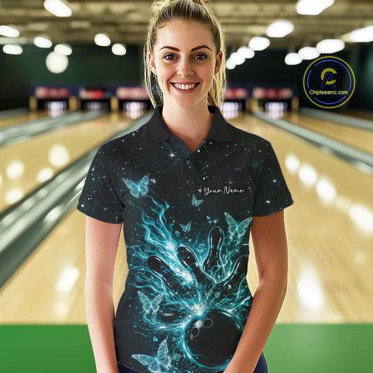 Female model wearing a black and turquoise blue bowling polo shirt at the lane with cosmic flaming strike artwork and glowing butterflies.
