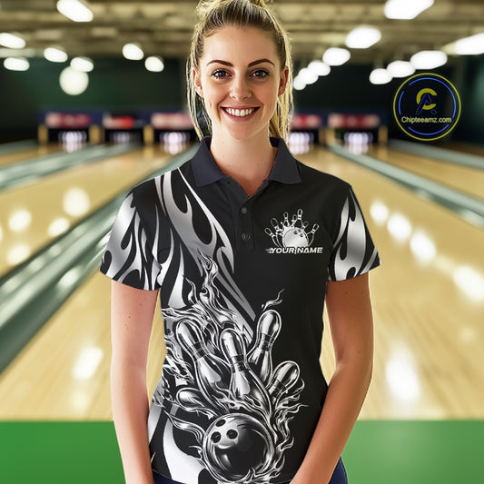 Female model front view in a bowling lane wearing a black polo shirt with a silver metal tribal flame bowling ball striking pins in an intense sports action scene.