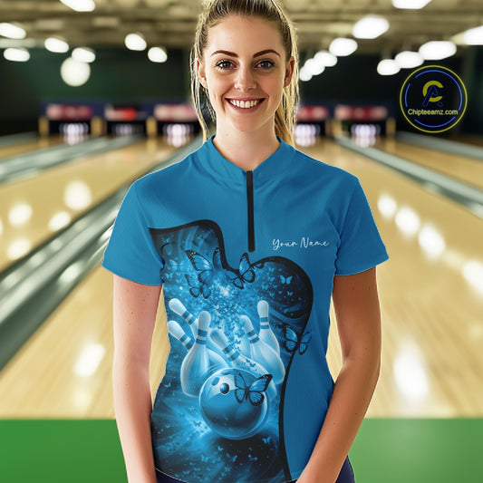 Woman wearing a blue bowling shirt with a design in a bowling alley.