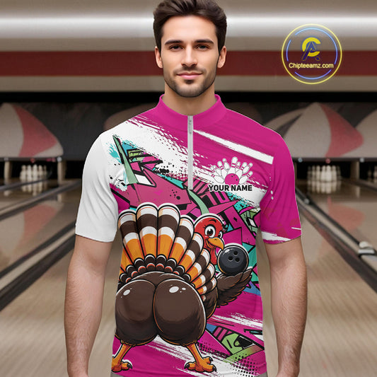 Front view of a male model wearing a pink custom quarter zip bowling shirt with a funny graffiti turkey holding a bowling ball, paint splatter accents in a bowling alley.