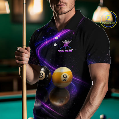 A man wearing a black short-sleeve polo shirt with a purple and blue galaxy print, featuring a crown logo and the text 'YOUR NAME' on the chest. He is holding a pool cue in a dimly lit pool hall environment.