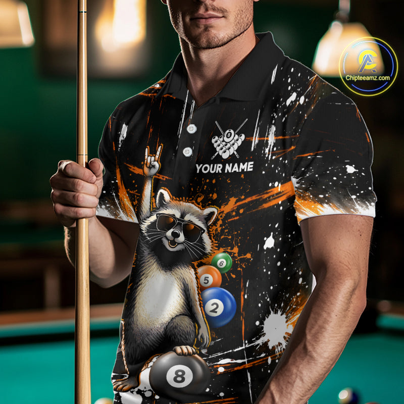 Person wearing a shirt with a raccoon design holding a pool cue in front of a pool table.