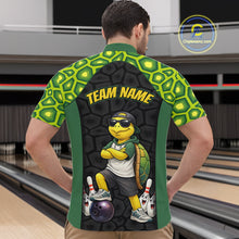 Load image into Gallery viewer, A man viewed from behind wearing a custom bowling shirt with a green and yellow turtle pattern on the sleeves and shoulders, a dark gray textured back panel, and a cartoon turtle graphic with the text 'TEAM NAME'. The background shows bowling lanes.