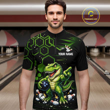 Load image into Gallery viewer, A man wearing a black short-sleeve bowling jersey with a green cartoon dinosaur graphic, bowling pins, and the text 'YOUR NAME' on the chest. The background shows a blurred bowling alley.