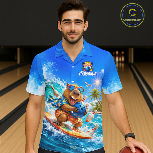 Man wearing a blue shirt with a bear surfing design in a bowling alley.