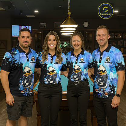 Four people standing together in a dimly lit indoor venue, wearing matching blue and black polo shirts with a large cartoon duck graphic and the text 'YOUR NAME'  on the chest.