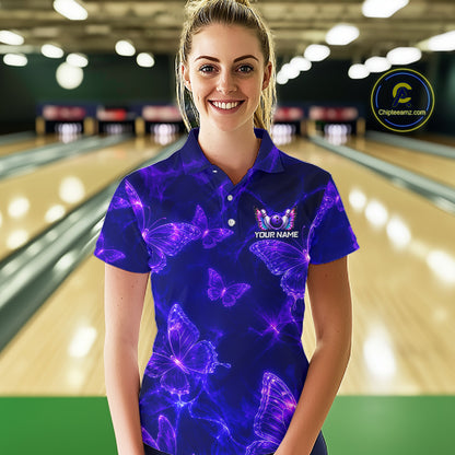 A woman stands in a bowling alley wearing a short-sleeve polo shirt with a vibrant purple and blue neon butterfly pattern. The shirt features a custom graphic with a butterfly, the text 'YOUR NAME'