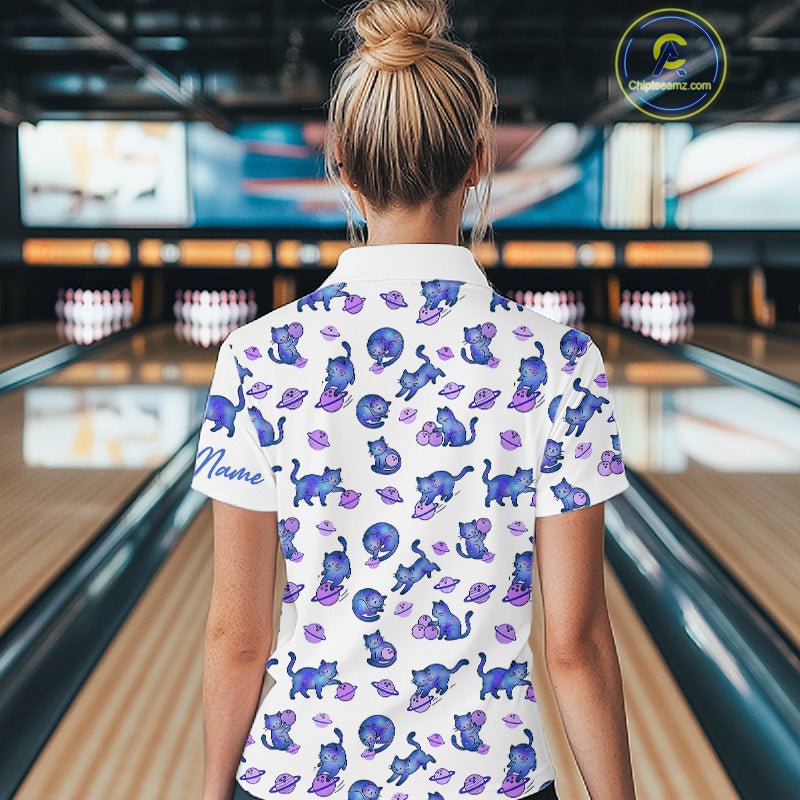Woman wearing a white shirt with blue cat pattern in a bowling alley.