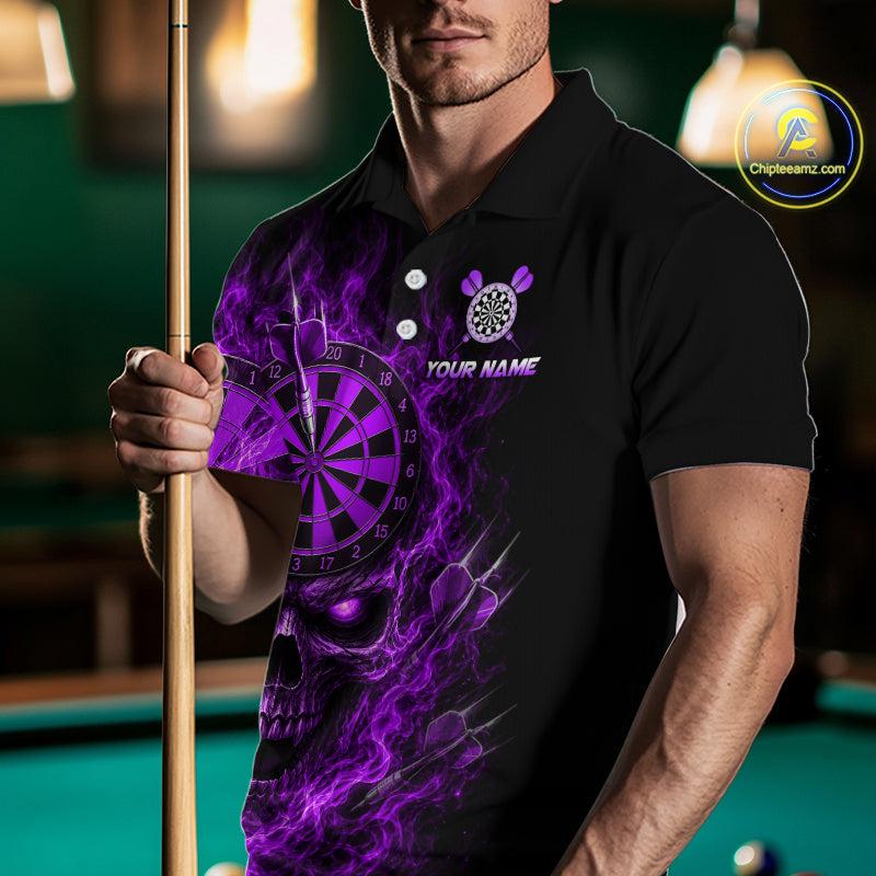 A man wearing a black polo shirt with a purple skull and dartboard graphic, holding a pool cue in a dimly lit pool hall. The shirt features a custom name placeholder and a brand logo in the top right corner.
