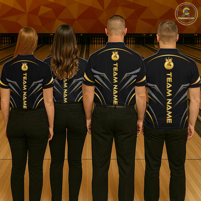 Four people standing in a bowling alley, viewed from behind, wearing matching dark navy short-sleeve team shirts with gold and gray graphic details and black pants. The shirts have vertical 'TEAM NAME' text and a circular logo on the upper back.