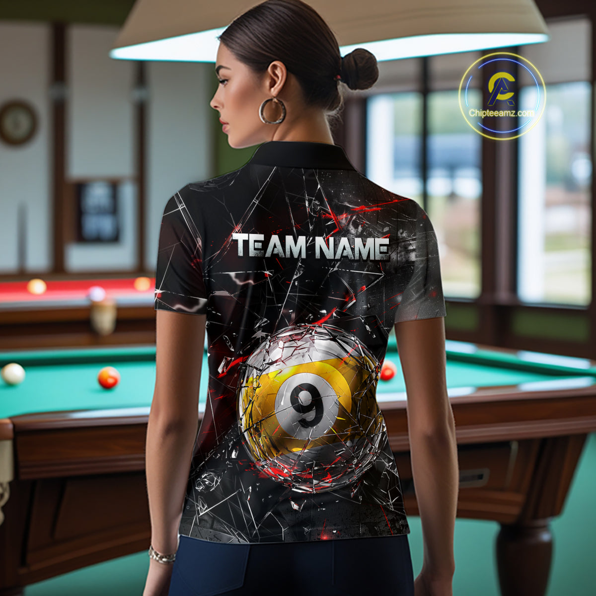 Woman wearing a black collared polo shirt with shattered glass graphics, red accent streaks, a custom name area, and a large cracked 9-ball illustration across the lower back.
