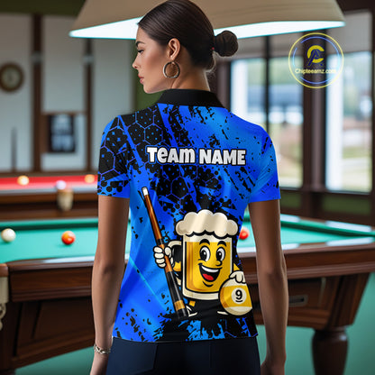 Woman wearing a bright blue billiards polo with black splatter graphics, custom “TEAM NAME” text, and a smiling beer mug mascot holding a pool cue.