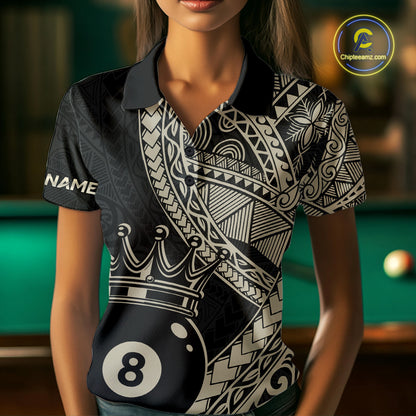 Women wearing a black and gold patterned shirt with an 8-ball design, standing in front of a pool table.