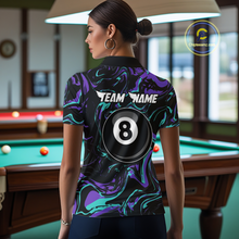 Load image into Gallery viewer, Back view of a woman wearing a black billiards polo with teal and purple marble swirls, “TEAM NAME” text, and a large 8-ball graphic.