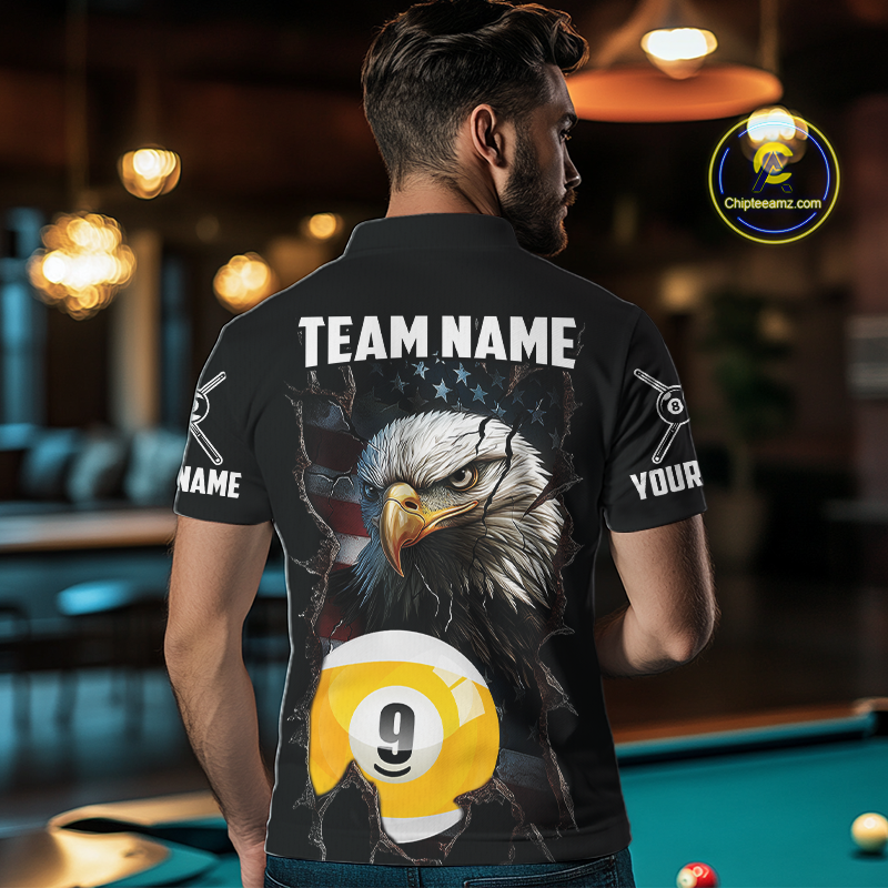 Man wearing a black shirt with an american flag eagle 9 ball and pool ball design, standing in a bar.