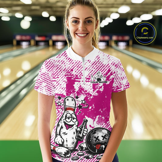 Front view female model in pink and white bowling quarter zip shirt inside bowling lane, playful bowling pin beer drinking graphic artwork