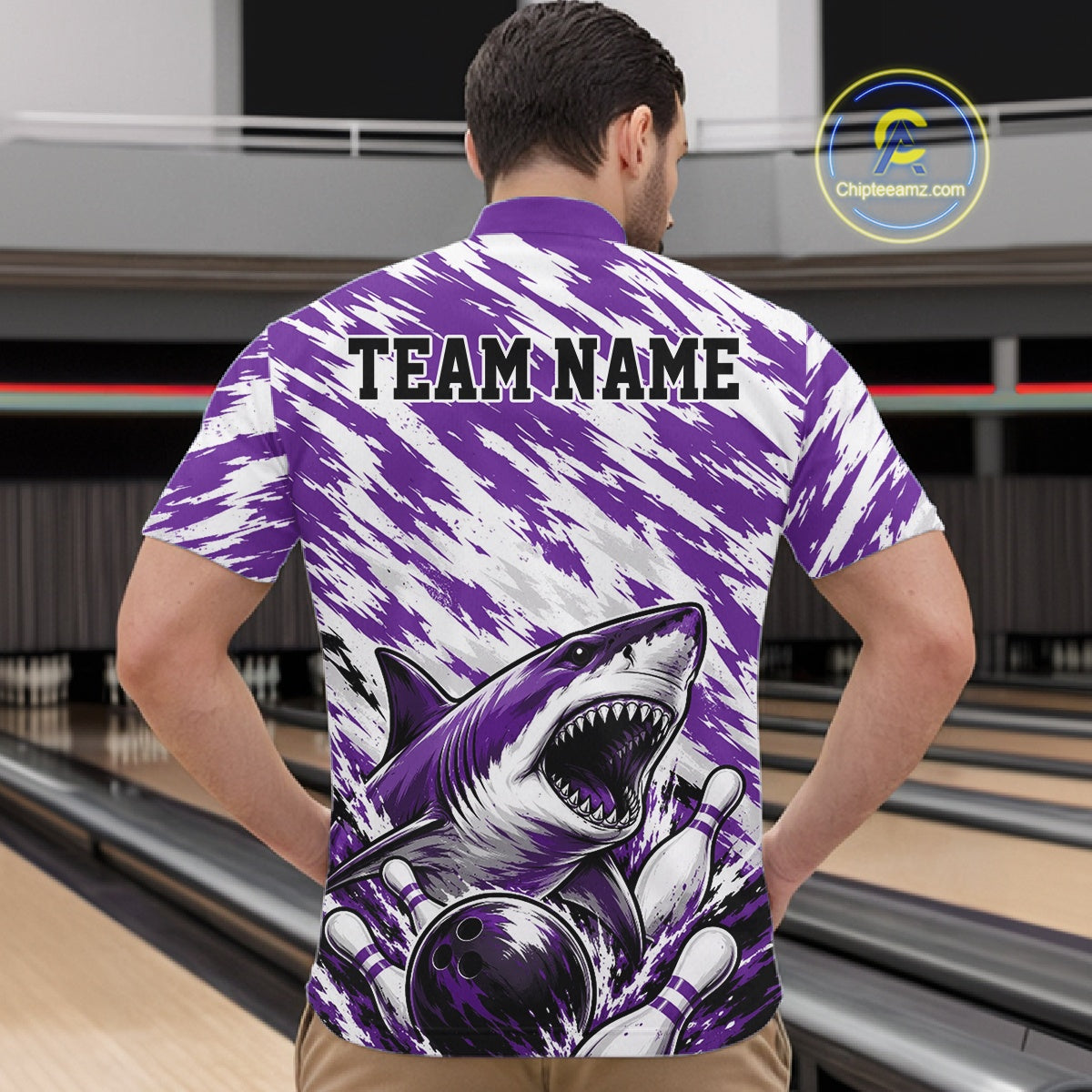 Person wearing a purple and white patterned shirt with a shark design and 'TEAM NAME' text, standing in a bowling alley.