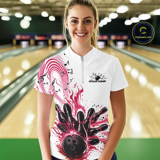 Female model wearing a white and pink bowling quarter-zip shirt at the bowling lane with musical bowling graphics.