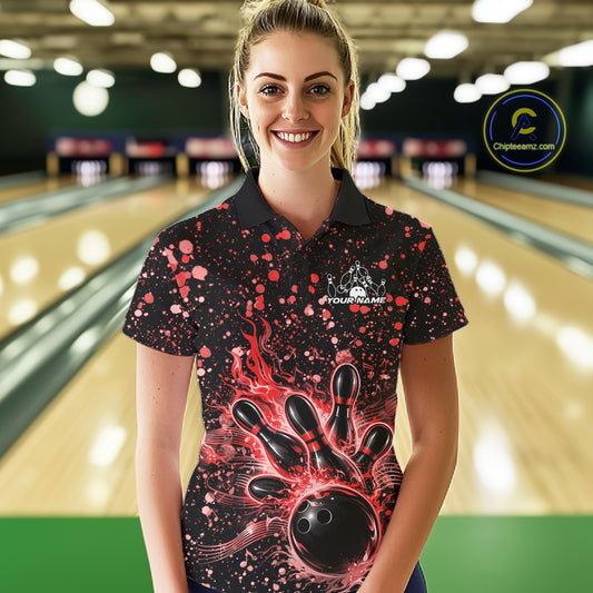 Female model wearing a black bowling polo shirt at the lane with red paint splatter details and bowling strike graphics.