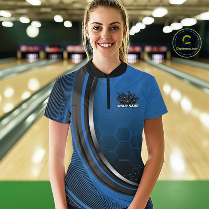 Female model at the bowling lane wearing a black and blue bowling quarter zip with honeycomb artwork and a flaming bowling action scene.