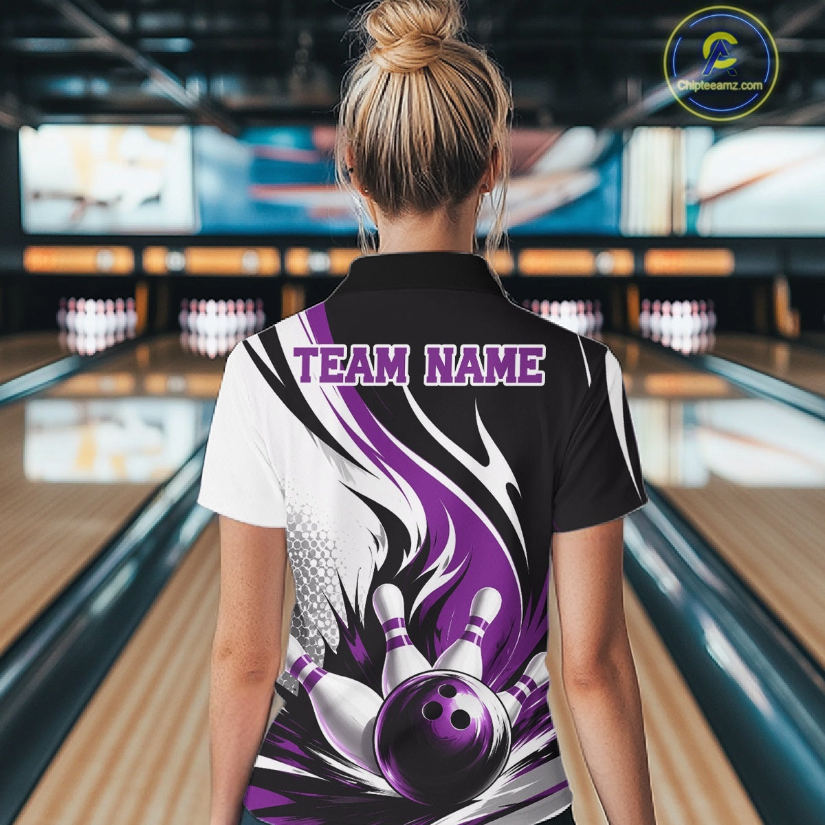 Back view of a female model wearing a white, black, and purple bowling quarter zip shirt featuring a flaming bowling ball striking pins in a bowling lane.