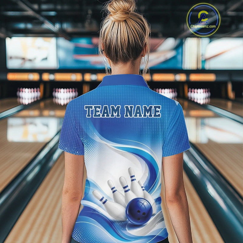 Female model standing in a bowling lane showing the back of a white and blue bowling polo shirt with abstract wave lines and a glossy bowling ball striking pins graphic.