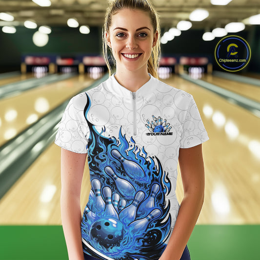 Front view female model at bowling lane wearing white and blue quarter zip shirt showing flaming bowling ball crashing into pins with energetic fire illustration.