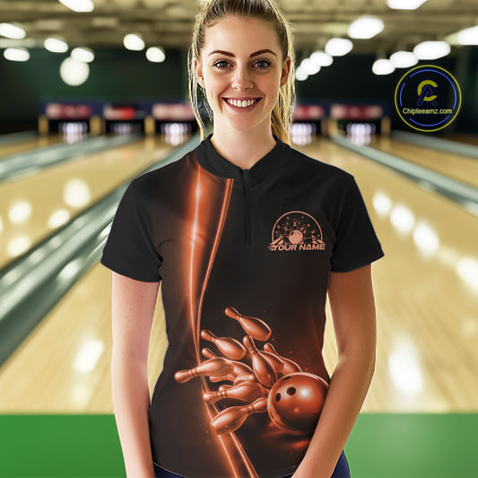 Front view of a female model in a bowling lane wearing a black quarter-zip shirt with orange bowling ball and pins design and clean sporty visuals.