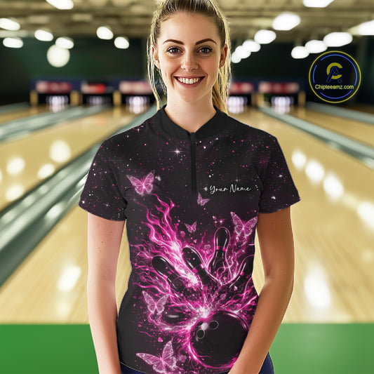 Female model in a black and pink bowling quarter-zip shirt at the bowling lane with glowing butterfly strike artwork.