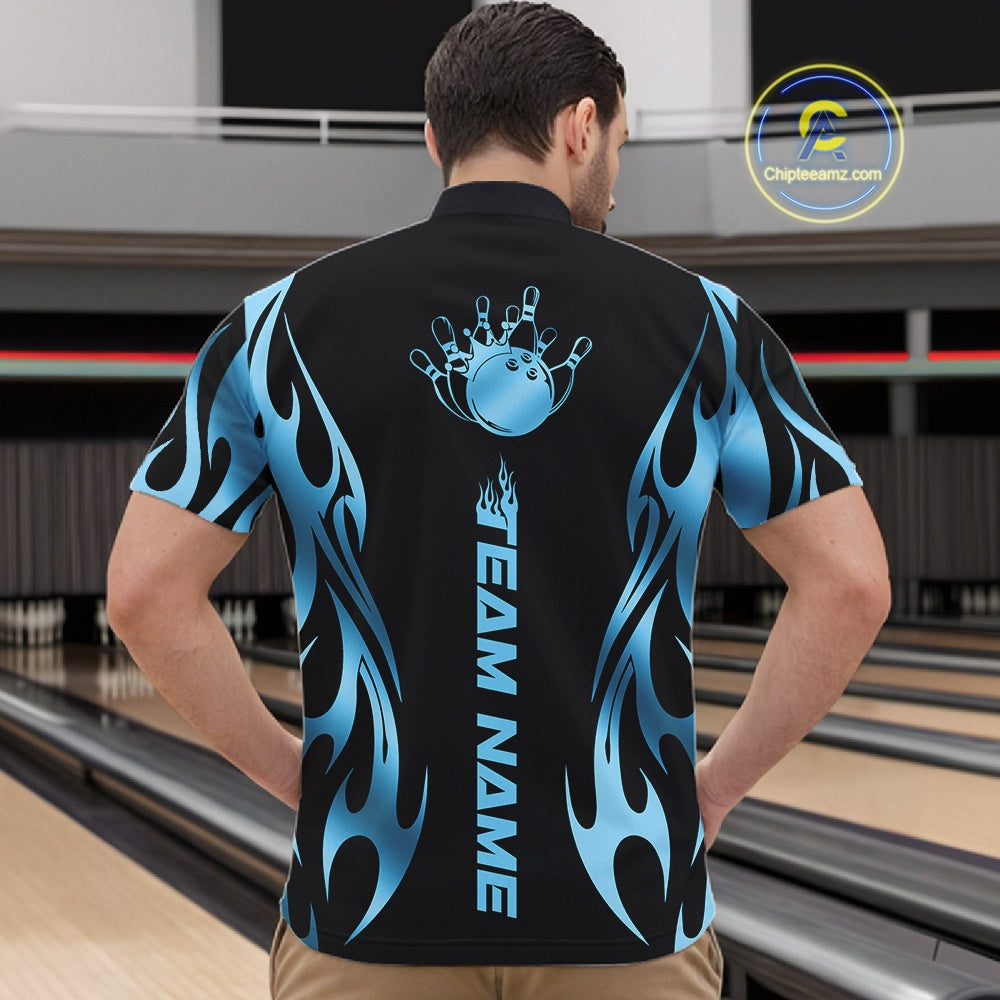 At the bowling lane, front view male model wearing black quarter zip shirt featuring blue tribal flame bowling ball striking pins in vivid motion artwork.