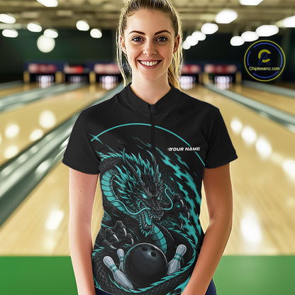 Front view of a happy female model in a bowling alley wearing a blue custom quarter-zip bowling shirt featuring an aggressive dragon with flames in a dynamic and energetic design.