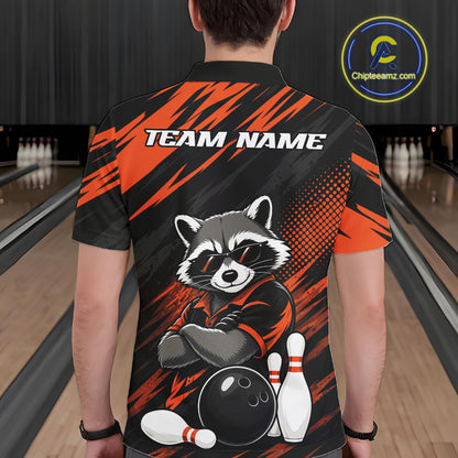 A man viewed from behind wearing a short-sleeve bowling shirt in a bowling alley. The shirt has a black and orange graphic design with a raccoon wearing sunglasses, bowling pins, a bowling ball, and the text 'TEAM NAME' across the upper back.