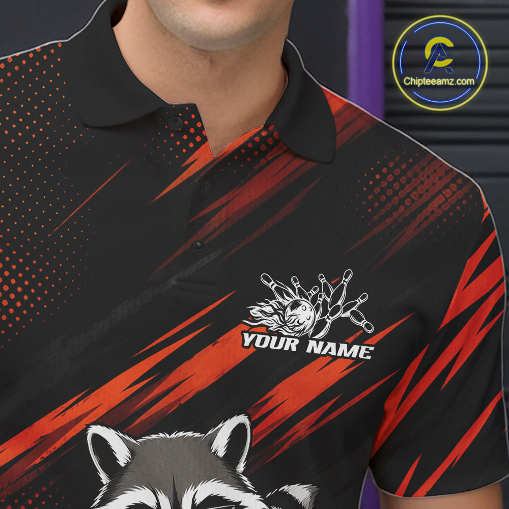 A close-up of a black short-sleeve polo shirt with red and orange graphic stripes, a white custom graphic on the chest, and a raccoon illustration at the bottom. The model is cropped from the chin down, and a circular 'Chipteamz logo.