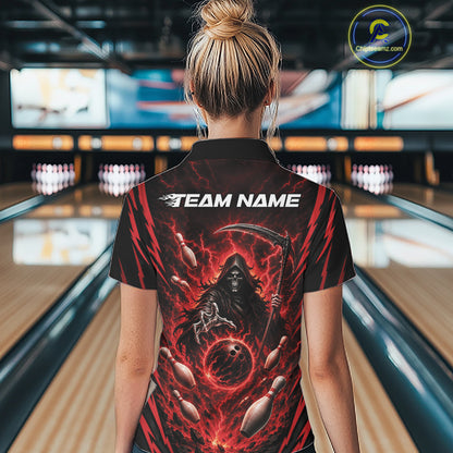 A woman viewed from behind wearing a black short-sleeve quarter zip bowling shirt with a fiery red and black grim reaper graphic and the text 'TEAM NAME' on the back, standing in a bowling alley.