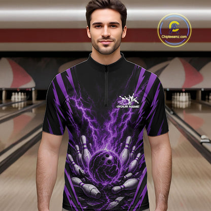 A man wearing a black short-sleeve bowling quarter zip shirt with a purple lightning-bolt and bowling pins graphic, standing in a bowling alley.