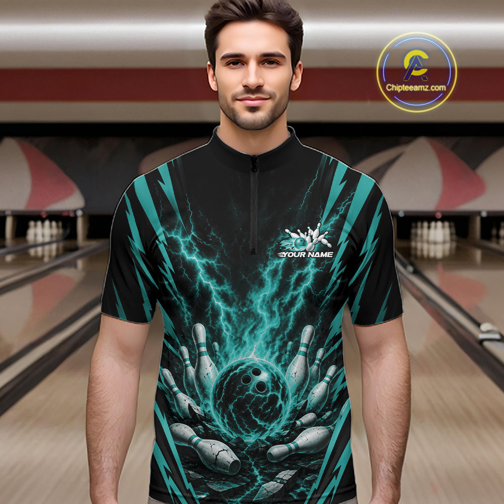 A man wearing a black short-sleeve quarter zip bowling shirt with a teal and black lightning-bolt and bowling pins graphic, standing in a bowling alley. 
