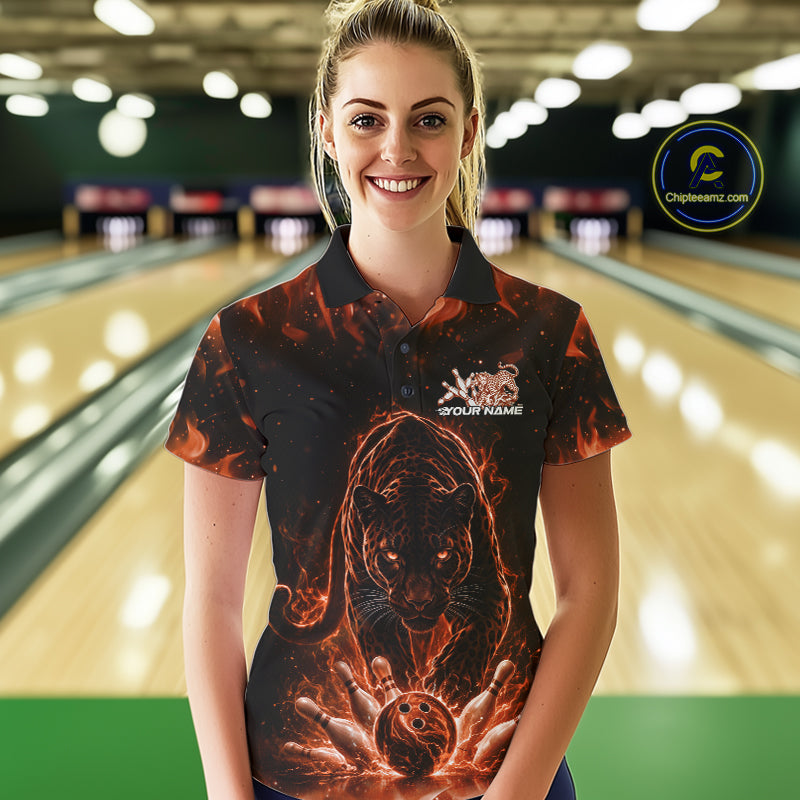 Front view of a female model in a bowling lane wearing a black polo shirt with glowing orange electric panther and bowling ball striking pins illustration.