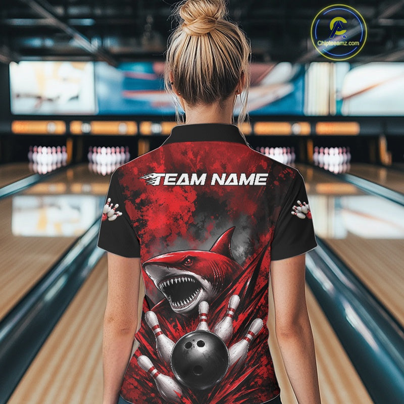 Person wearing a bowling shirt with a shark design and 'Team Name' text in a bowling alley.