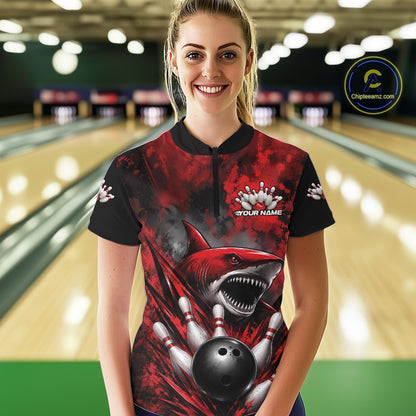 Woman wearing a red and black bowling shirt with a shark design in a bowling alley.