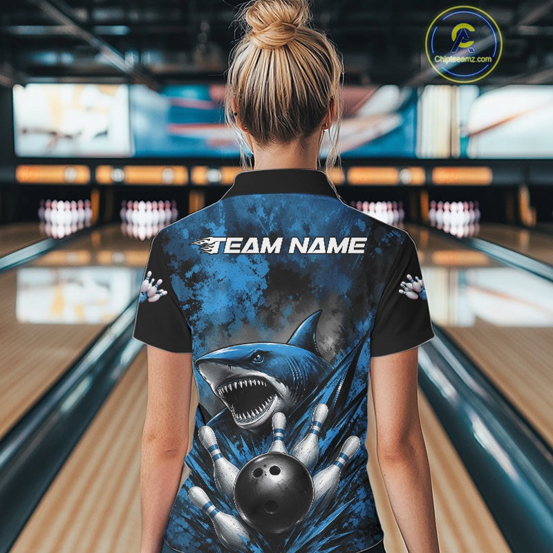 Person wearing a bowling shirt with a shark design and 'Team Name' text in a bowling alley.