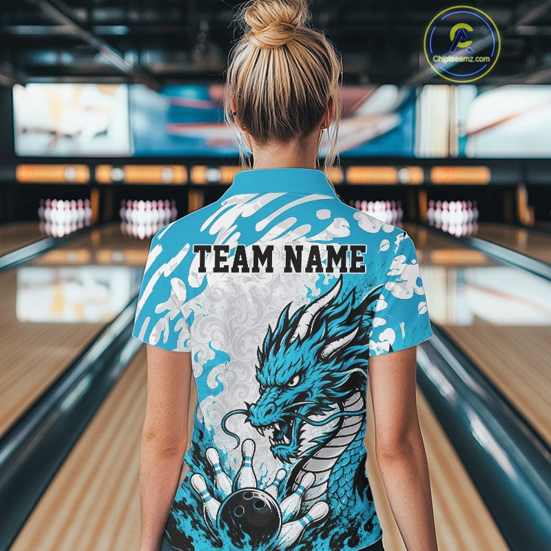Person wearing a blue bowling shirt with a dragon design and 'TEAM NAME' text in a bowling alley.