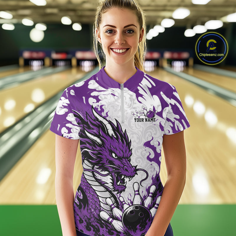 Person wearing a purple bowling shirt with dragon design in a bowling alley.