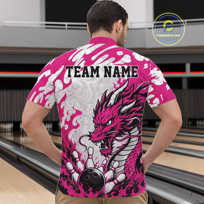 Person wearing a pink and white bowling shirt with a dragon design and 'TEAM NAME' text, standing in a bowling alley.
