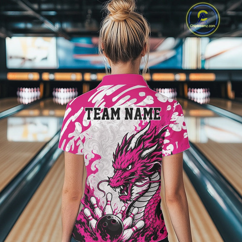 Person wearing a pink bowling shirt with dragon design and 'TEAM NAME' text in a bowling alley.