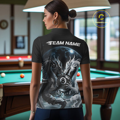A woman stands in a billiards room wearing a black short-sleeve polo shirt with a large back graphic of a dragon holding an 8-ball under the text 'TEAM NAME'. 