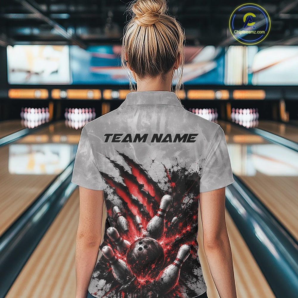 Back view of a female model wearing a gray bowling quarter zip shirt featuring a dramatic red bowling ball striking pins graphic with claw-mark artwork in a bowling lane.
