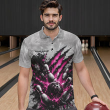 Load image into Gallery viewer, Front view of a male model wearing a gray bowling polo shirt featuring a dramatic pink bowling ball striking pins graphic with claw-mark artwork at a bowling lane.