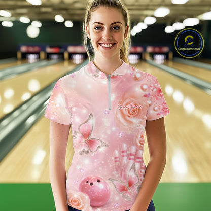 Female model at a bowling lane wearing a quarter-zip bowling shirt with sparkling butterfly motifs, diamonds, bowling pins, and a bowling ball design.
