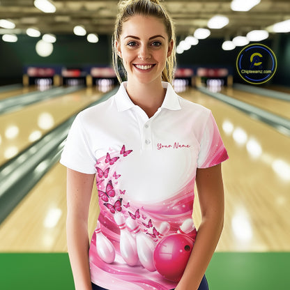 Female model in a white and pink bowling polo shirt featuring butterfly accents and bowling graphics inside a bowling alley.